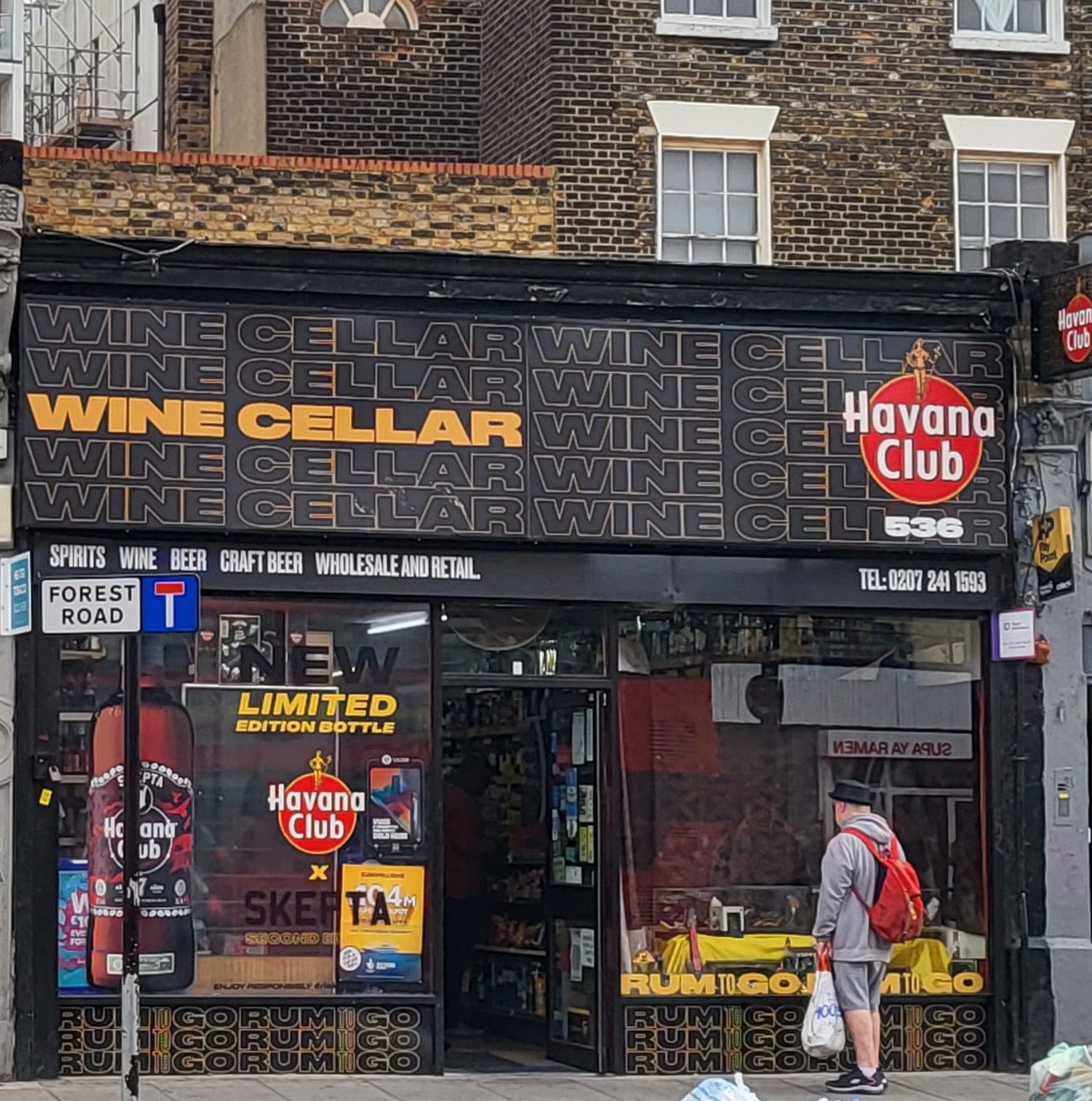 Wine Cellar off licence at 536 Kingsland Road, Dalston: black shopfront with the amber ‘Wine Cellar’ lettering and strapline spirits, wine, beer, craft beer, wholesale and retail